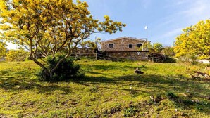 A rustic stone building with a sloped roof, surrounded by a grassy area with trees. - Holiday apartment with air conditioning, internet and pool (Imperia)