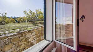 A room with a stone wall, a window with a view of trees and a clear sky. - Holiday apartment with air conditioning, internet and pool (Imperia)
