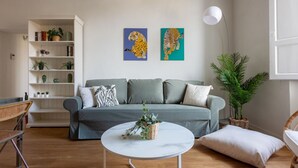 A living room with a sofa, a coffee table, a bookshelf, and two wall-mounted paintings. - Libertà Bright and Stylish (Florence)