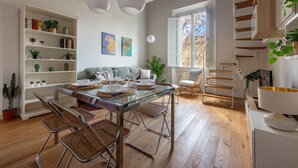 A modern dining area with a glass table, metal chairs, and a bookshelf filled with books and plants. - Libertà Bright and Stylish (Florence)