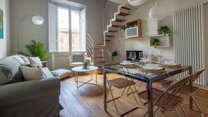 A modern living room with a sofa, a dining table set for six, a staircase, and a radiator. - Libertà Bright and Stylish (Florence)