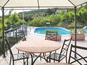 A covered outdoor area with a pool, seating, and a view of a hillside. - Holiday apartment with air conditioning, internet and pool (Imperia)
