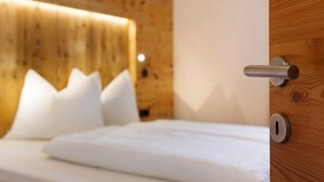 Ein Bett mit weißer Bettwäsche, einem hölzernen Kopfteil und einer Tür mit Metallbeschlag.
