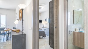 Ett modernt hotellrum med en matplats, en säng, ett badrum med en tvättställ av marmor och utsikt över staden.