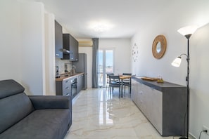 A modern kitchen with a dining area, a sofa, and a lamp.