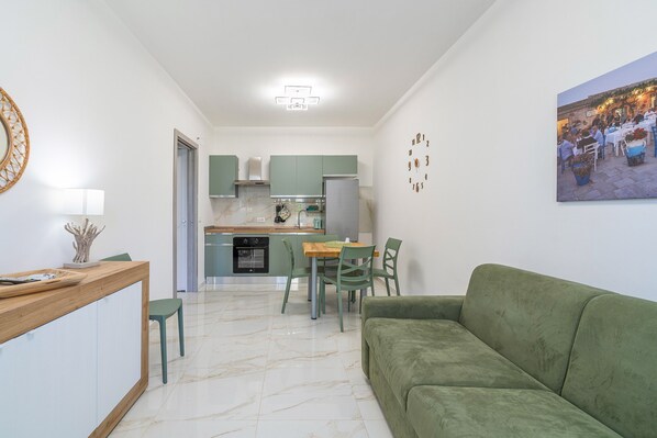 Ein modernes Wohnzimmer mit einem grünen Sofa, einem Holztisch und einem Essbereich mit grünen Stühlen und einem Tisch.