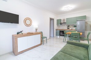 Un salon moderne avec un canapé vert, une table basse en bois et un téléviseur fixé au mur.