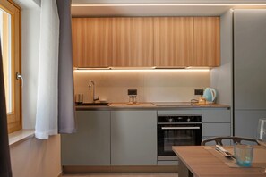 A compact kitchen with wooden cabinets, a built-in oven, and a small dining area. - Apartment 'Rosa Blu' with Balcony and Wi-Fi (Piano)