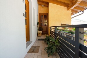 A balcony with a wooden railing, a welcome mat, and potted plants. - Apartment 'Rosa Blu' with Balcony and Wi-Fi (Piano)