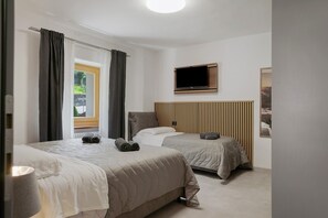 Une chambre d’hôtel avec deux lits, une télévision, une fenêtre avec des rideaux et un radiateur.