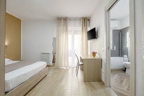 A bedroom with a bed, a desk, a chair, a TV, and a bathroom visible through an open door. - Apartment 'Kome's' with Balcony, Wi-Fi and Air Conditioning (Palermo)