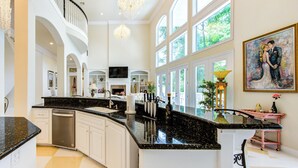 A spacious kitchen with a curved island, white cabinetry, and a large window providing natural light. - 10 Serene Acres: Your Perfect Micro Wedding Escape (Huntsville)