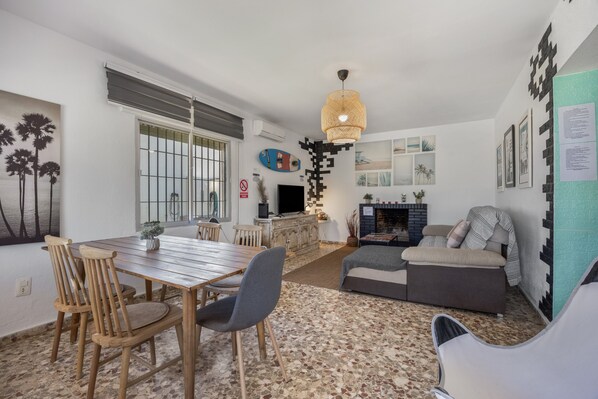 Uma área de refeições com mesa e cadeiras de madeira, um sofá e uma lareira.