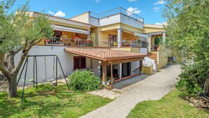 A two-story house with a balcony, a covered patio, and a stone pathway leading to the entrance. - Apartment 'Agata Verde' with Views of the Hills and Garden (Porto Ottiolu)
