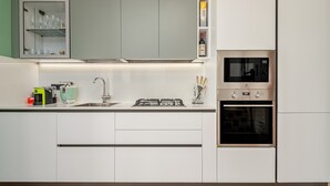 A modern kitchen with white cabinets, a built-in microwave, and a gas stove. - Apartment 'Agata Verde' with Views of the Hills and Garden (Porto Ottiolu)