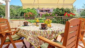 A patio with a table set for two, surrounded by chairs, with a view of a house and greenery in the background. - Apartment 'Agata Verde' with Views of the Hills and Garden (Porto Ottiolu)