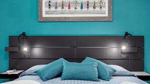 A bed with teal pillows, a framed artwork above, and bedside lamps. - Apartment 'Agata Verde' with Views of the Hills and Garden (Porto Ottiolu)