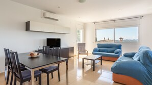 A modern living space with a dining area, a sofa, and a television. - Holiday Home 'Azzure' with Sea View, Wi-Fi and Air Conditioning (Lloret de Mar)