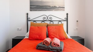 A bed with a red quilt, two pillows, and rolled towels. - Holiday Home 'Azzure' with Sea View, Wi-Fi and Air Conditioning (Lloret de Mar)