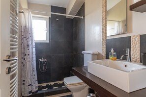 Ein Badezimmer mit Dusche, Toilette und Waschbecken.