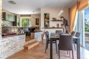 Eine moderne Küche mit Essbereich, Kamin und Blick ins Freie.
