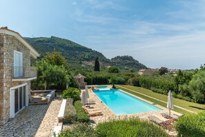 Un bâtiment en pierre doté d’une piscine, d’un espace extérieur aménagé et offrant une vue sur un paysage vallonné.