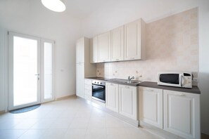 A kitchen with white cabinets, a microwave, an oven, and a sink.