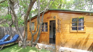 Una cabaña de madera con base de piedra, una puerta de madera y una ventana.