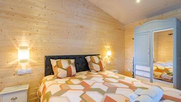 Een kamer met houten lambrisering, een bed, bedlampen, een kast en een spiegel.