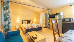 Ein gemütliches Zimmer mit Bett, einer Sitzecke, einem Tisch, einem Stuhl, einer Küchenzeile und einem Kleiderschrank.