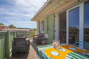 A deck with outdoor furniture, a table with a patterned tablecloth, and a view of the surrounding area. - Apartment 'Au Calme Avec Terrasse' with Private Terrace and Wi-Fi (Cogolin)