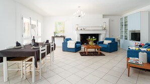 A modern living room with a dining area, a fireplace, and a television. - Apartment 'La Vela Rossa' with Shared Pool, Wi-Fi and Air Conditioning (Sas Linnas Siccas)