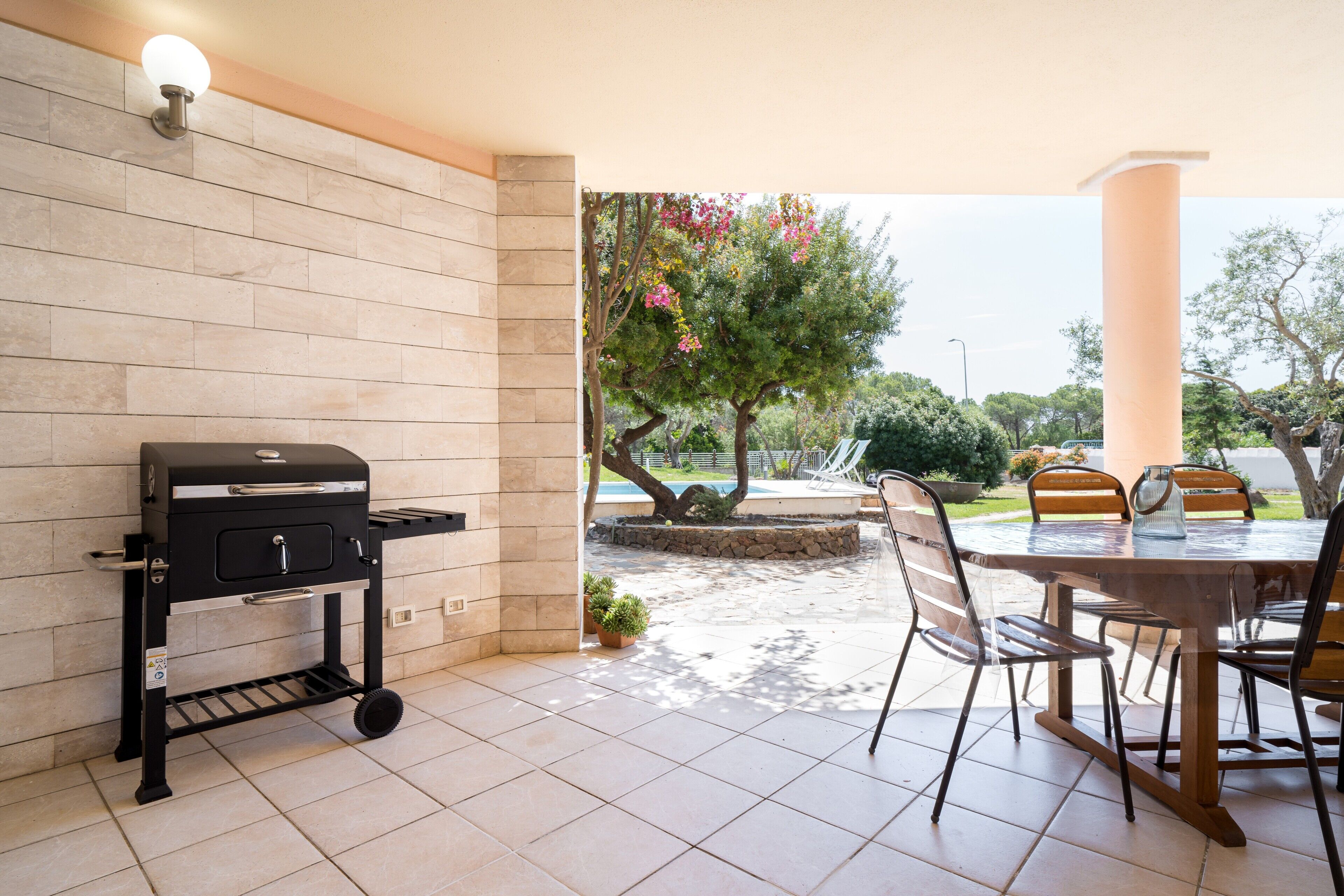 Un patio con una parrilla, sillas y una mesa.