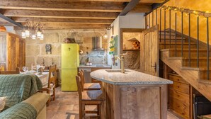 Una cocina rústica con una isla de madera, paredes de piedra y un refrigerador verde.