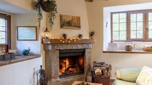 Una habitación acogedora con chimenea, una ventana con vistas, una cama y una mesa con una cesta.