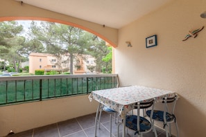 A balcony with a table and chairs, a view of buildings, and a green mesh fence. - Studio 'Chez Alain Et Martine' with Private Terrace (Saint-Mandrier-sur-Mer)