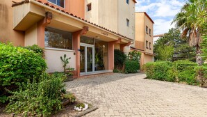 A building with a sign reading 'LAGOS' at the entrance, a paved driveway, and surrounding greenery.