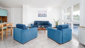 Una sala de estar con un sofá, dos sillones, una mesa de centro y un cuadro en la pared.