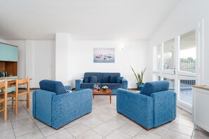 Un salon comprenant un canapé, deux fauteuils, une table basse et un tableau accroché au mur.