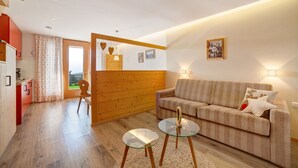 Ein modernes Wohnzimmer mit einer Couch, einem Glastisch, Holzelementen und Blick durch eine Tür.