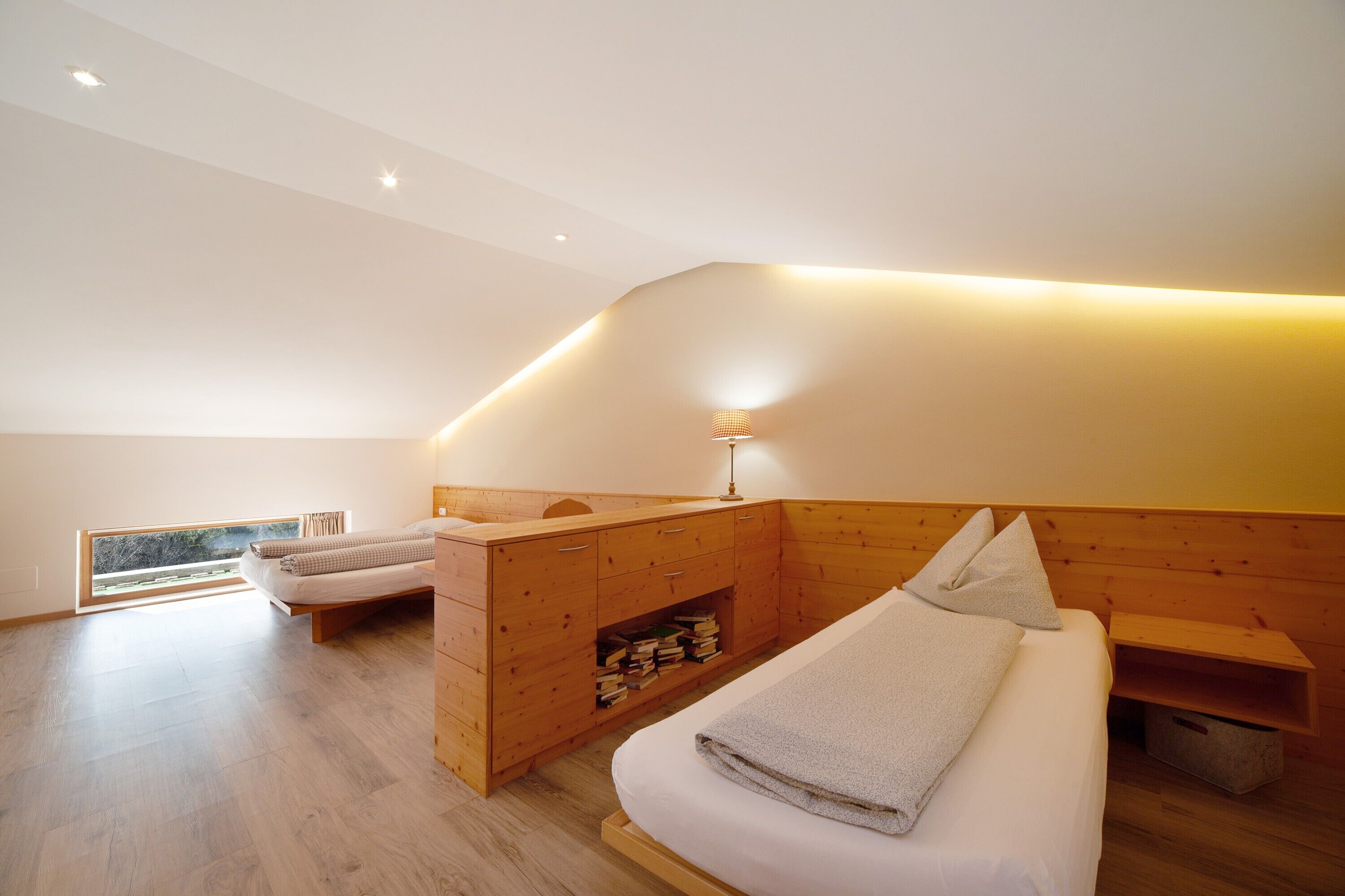 Une chambre moderne avec une tête de lit en bois, une table de chevet, une lampe et une vue sur l’extérieur.