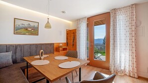 A dining area with a wooden table, two chairs, a sofa, and a painting on the wall.