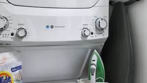A compact washer and dryer unit with a control panel, a bag of Tide detergent, and an iron on the counter. - Charming 2-bedroom townhome in Raleigh with AC, WiFi (Raleigh)