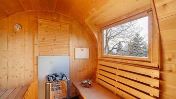 L’intérieur d’un chalet en bois comprend un sauna, une fenêtre donnant sur la forêt et un banc en bois.
