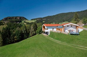 A modern house with a red roof, surrounded by green hills and a clear sky. - Apartment 'Heimat' with Mountain View, Shared Terrace and Wi-Fi (Verano)