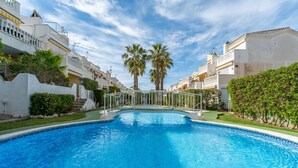 A swimming pool with a metal bridge, surrounded by buildings with balconies and palm trees. - Apartment 'A Un Paso Del Mar' with Shared Pool and Balcony (Guardamar del segura)