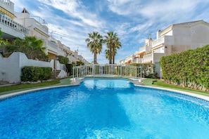 Una piscina con un puente metálico, rodeada de edificios con balcones y palmeras.