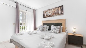 A hotel room with a bed, a nightstand, a wall-mounted lamp, and a window with curtains. - Apartment 'A Un Paso Del Mar' with Shared Pool and Balcony (Guardamar del segura)