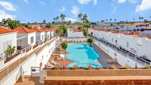 Ein Resort mit Schwimmbad, Palmen und weißen Gebäuden mit roten Dächern.