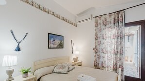 A bedroom with a bed, bedside tables, a lamp, a picture frame, a potted plant, and a window with curtains. - Apartment 'Lumia Sole' with Sea View, Wi-Fi and Air Conditioning (Sciacca)